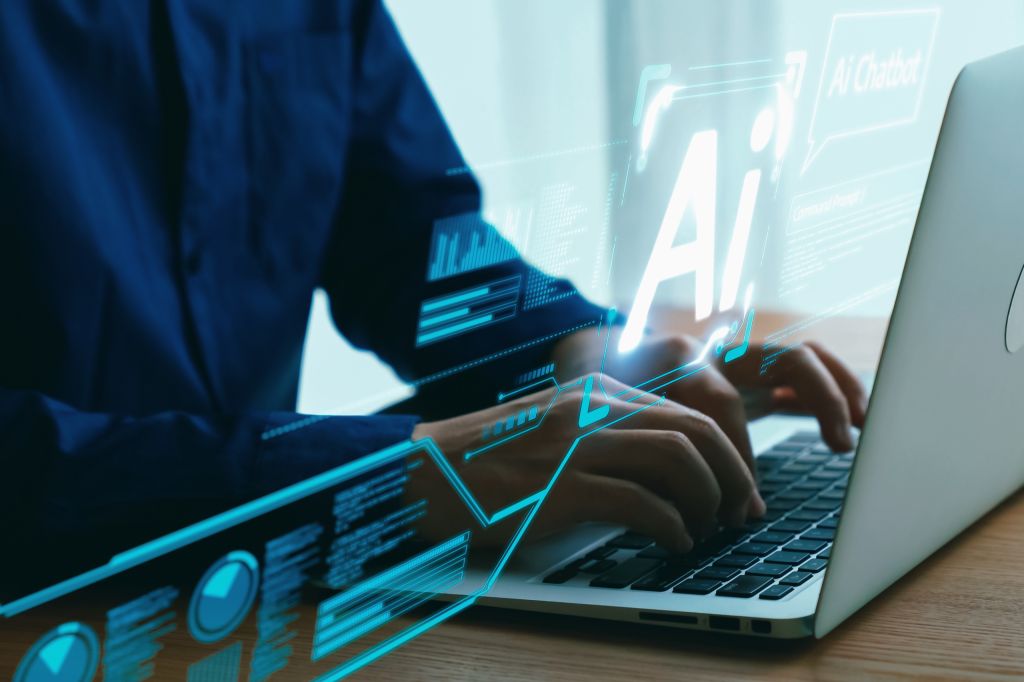Human interact with AI artificial intelligence virtual assistant UUID A person in a blue shirt types on a laptop, with a futuristic overlay of glowing blue graphics, including charts, data visualizations, and the letters "AI" to represent artificial intelligence.